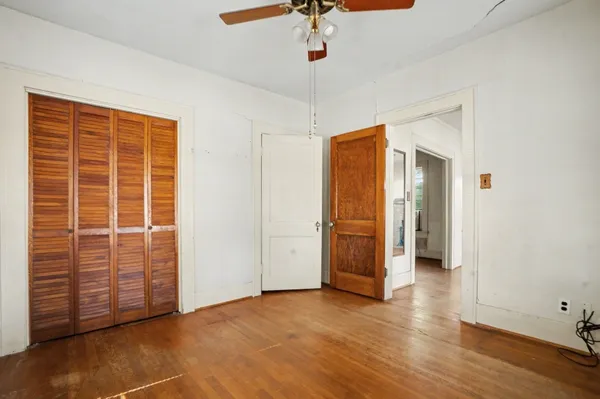 an empty room with wooden floor cabinet and windows