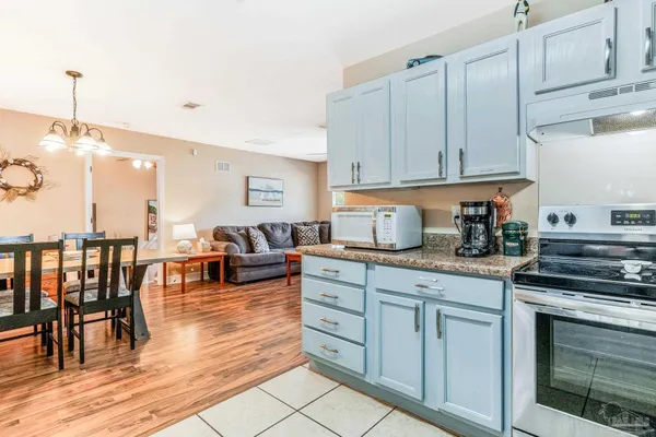 a kitchen with stainless steel appliances granite countertop a stove a sink dishwasher and white cabinets with wooden floor