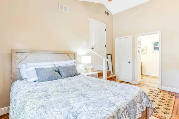 a bedroom with a large bed and wooden floor