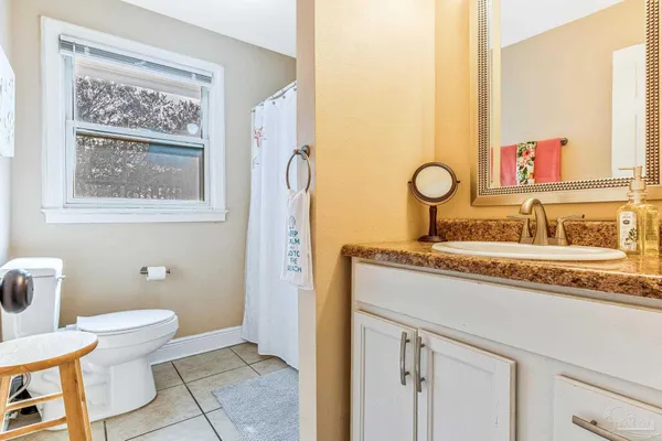 a bathroom with a granite countertop sink a toilet and a window