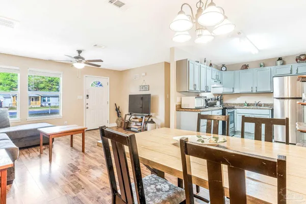 a room with stainless steel appliances kitchen island granite countertop a table chairs and a refrigerator