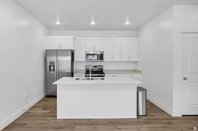 3115 South 200 West, Unit C201 Nibley, UT 84321 - Photo 3 of 23 Modern kitchen featuring white shaker cabinetry, stainless steel appliances, a center island with an undermount sink, recessed lighting, and wood-finish flooring