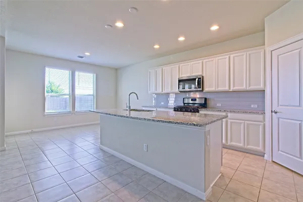 a kitchen with stainless steel appliances granite countertop a stove a sink and a refrigerator