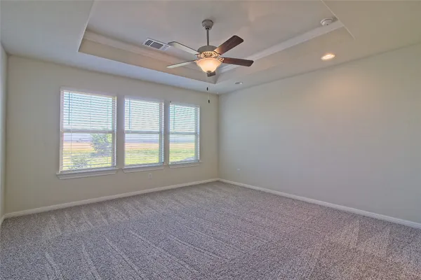 an empty room with a chandelier fan and windows