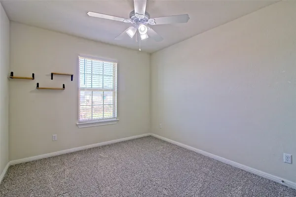 an empty room with windows and fan