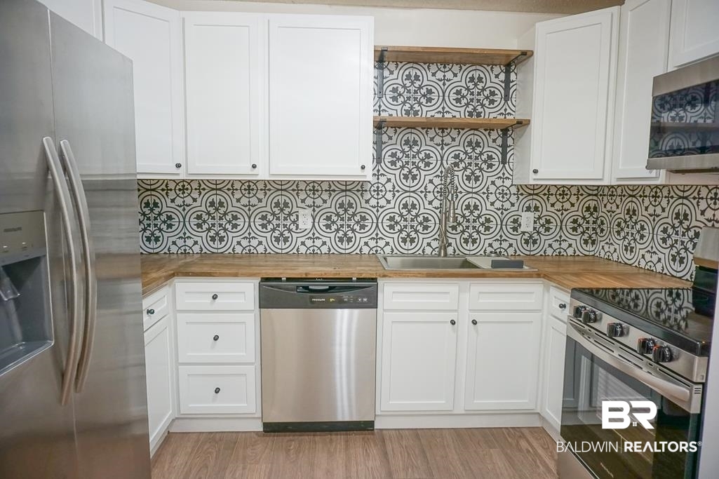 4159 Rebecca Road Mobile, AL 36609 - Photo 6 of 19 Kitchen with light wood-type flooring, backsplash, stainless steel appliances, and wooden counters