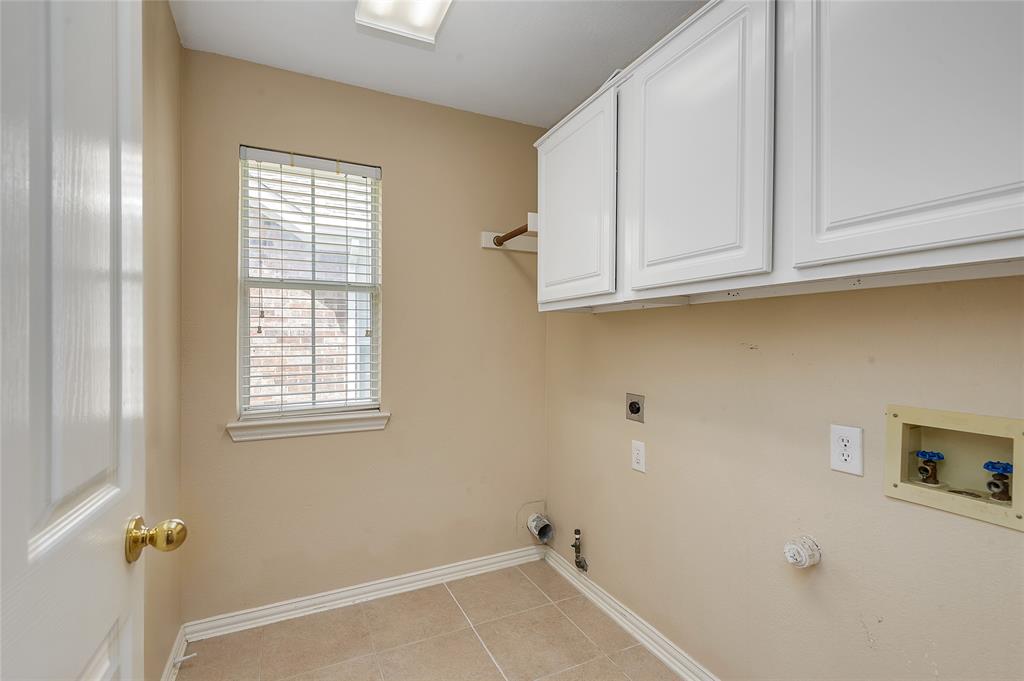1404 Ranch Hill Drive Irving, TX 75063 - Photo 17 of 31 Laundry room featuring light beige wall paint, white cabinetry, light-colored tile flooring, and a window with blinds