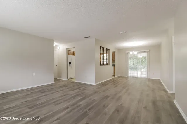 a view of an empty room with window and wooden floor