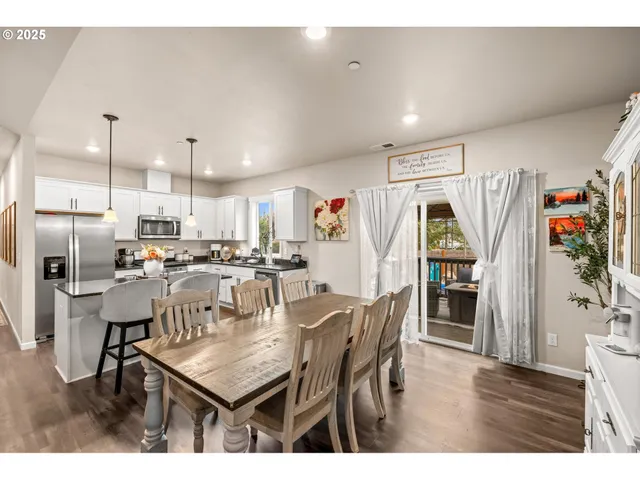 a dining hall with stainless steel appliances kitchen island granite countertop a table chairs and a kitchen view