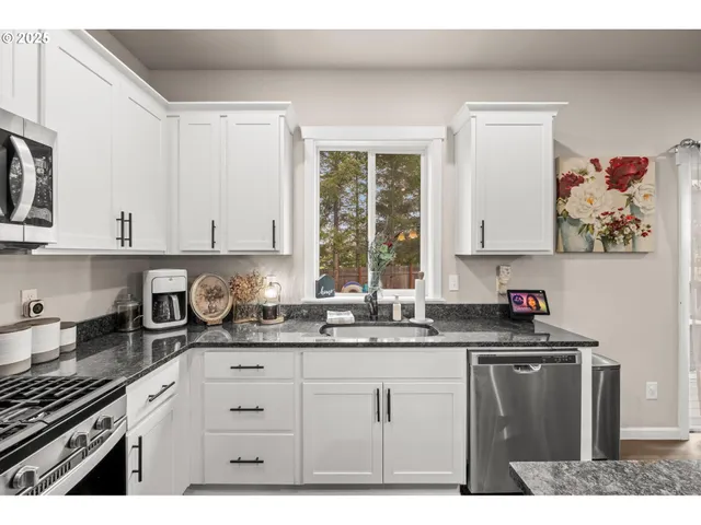 a kitchen with granite countertop a sink a stove and cabinets
