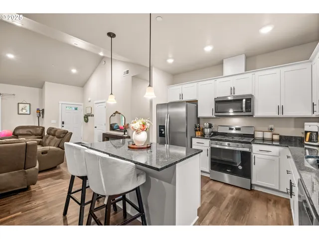 a kitchen with stainless steel appliances granite countertop a stove a sink a microwave a refrigerator and cabinets