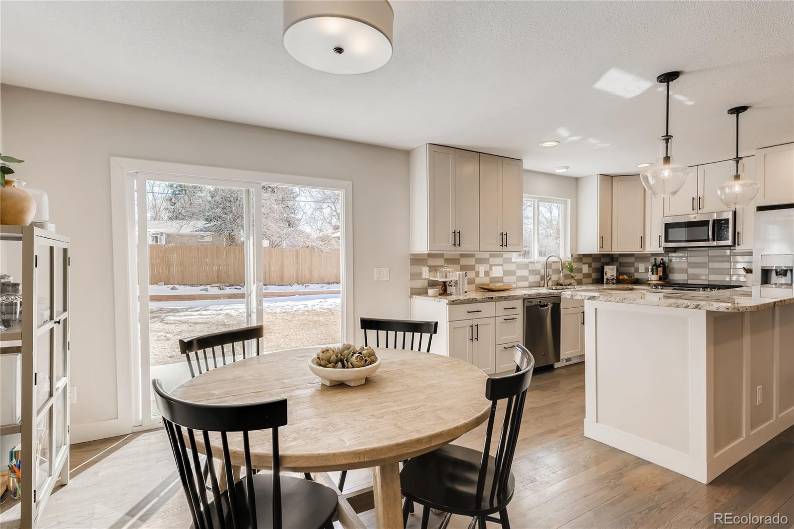 3530 East Orchard Road Centennial, CO 80121 - Photo 11 of 35 a kitchen with stainless steel appliances granite countertop a stove a refrigerator a white table and chairs with wooden floor