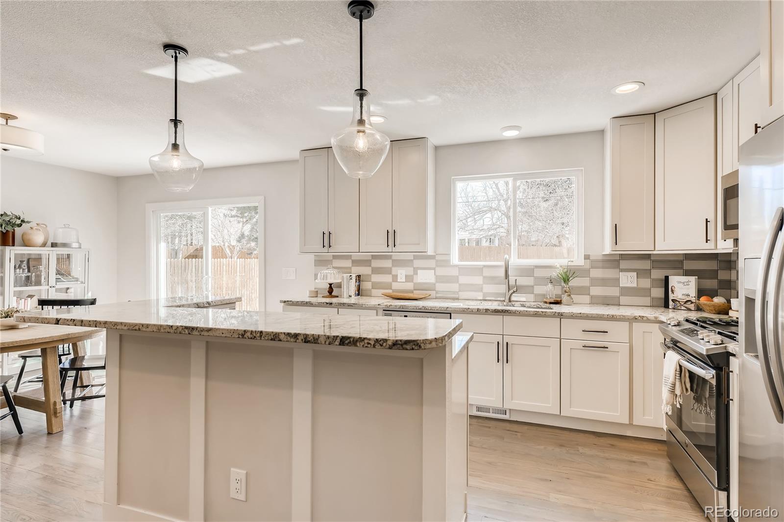 3530 East Orchard Road Centennial, CO 80121 - Photo 10 of 35 a kitchen with stainless steel appliances granite countertop a sink a stove a refrigerator and white cabinets with wooden floor