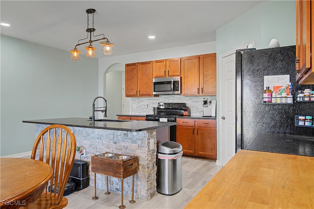 2613 Manzilla Lane Cape Coral, FL 33909 - Photo 5 of 42 a kitchen with stainless steel appliances granite countertop a stove top oven a sink a dining table and chairs