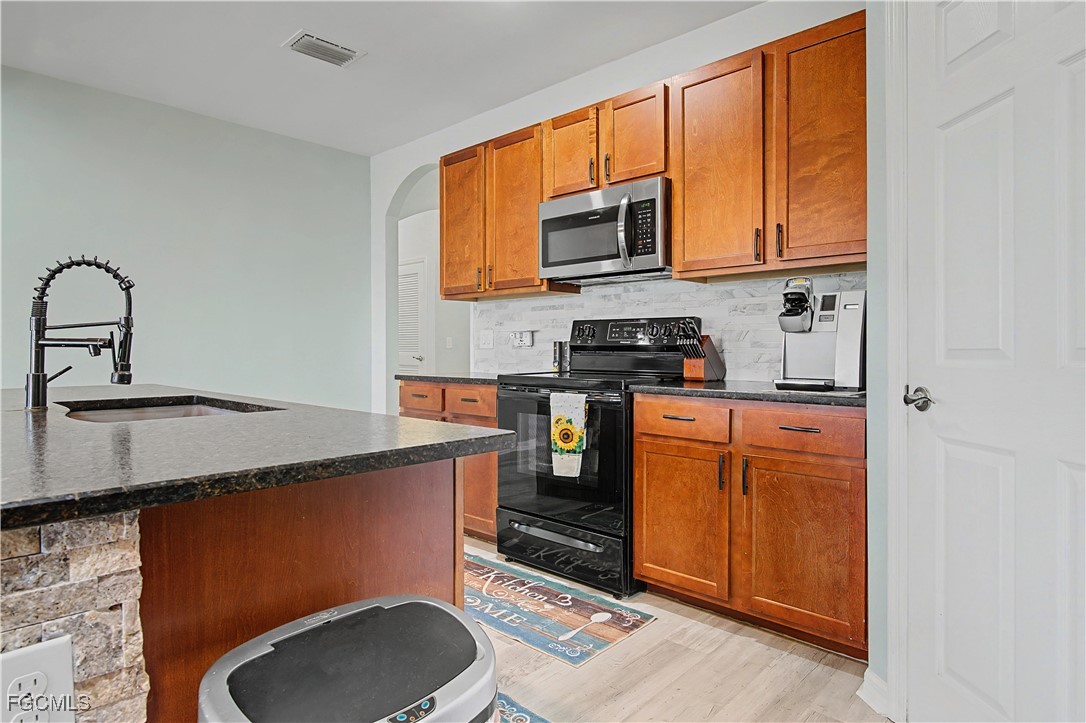 2613 Manzilla Lane Cape Coral, FL 33909 - Photo 6 of 42 a kitchen with stainless steel appliances a sink a stove cabinets and a microwave