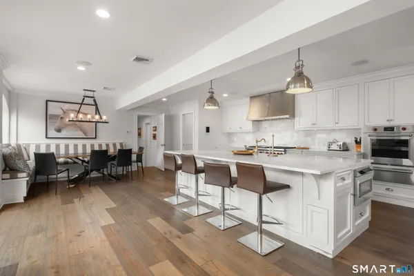 a living room with stainless steel appliances kitchen island granite countertop furniture and a wooden floor