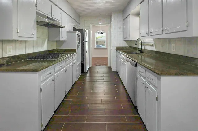a kitchen with granite countertop lots of counter space and stainless steel appliances