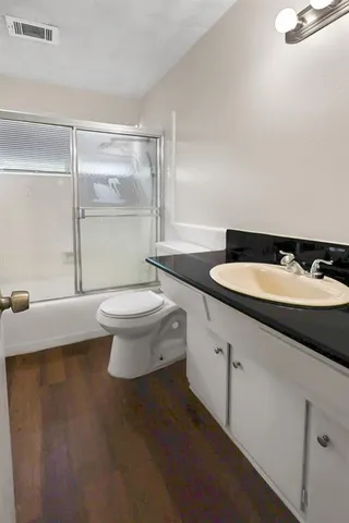 a bathroom with a granite countertop sink a toilet a mirror and shower