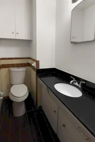 a bathroom with a granite countertop toilet sink and mirror