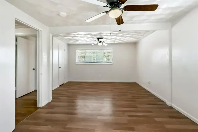 an empty room with wooden floor fan and windows