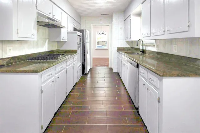 a kitchen with granite countertop lots of counter space and stainless steel appliances