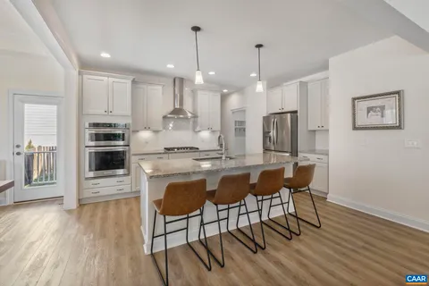 a kitchen with stainless steel appliances granite countertop a kitchen island a stove a refrigerator a oven a sink with a dining table and chairs