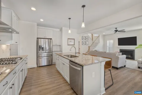 a kitchen with stainless steel appliances granite countertop a stove top oven a refrigerator a sink and a dining table with wooden floor