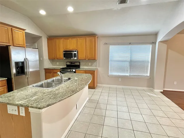 a kitchen with granite countertop a stove a sink and a refrigerator