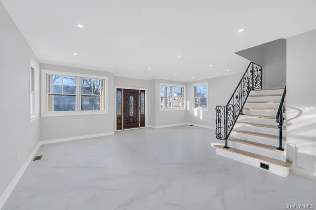 a view of an empty room with stairs and a window