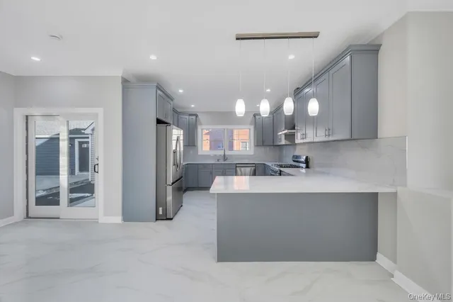 a large kitchen with a large counter top a sink stainless steel appliances and cabinets