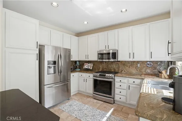 a kitchen with stainless steel appliances granite countertop a refrigerator stove and white cabinets