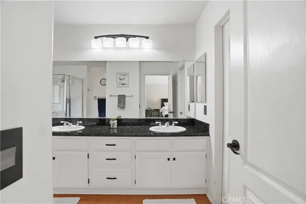 a bathroom with a granite countertop double vanity sink and mirror