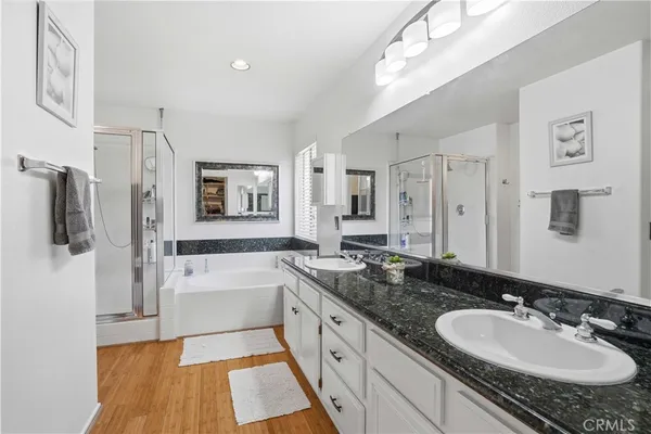 a spacious bathroom with a granite countertop double vanity sink a mirror and shower