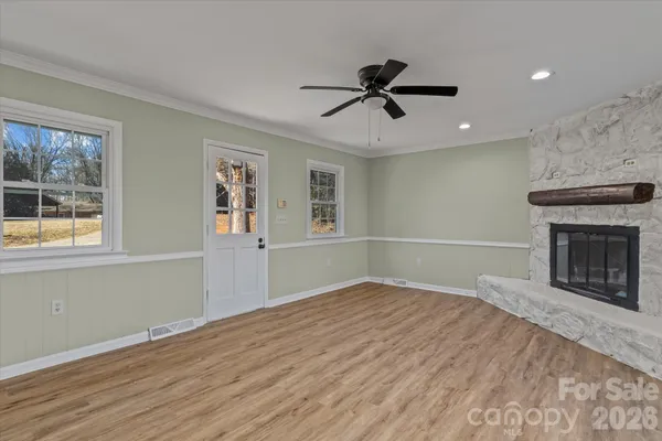 a view of an empty room with window and wooden floor