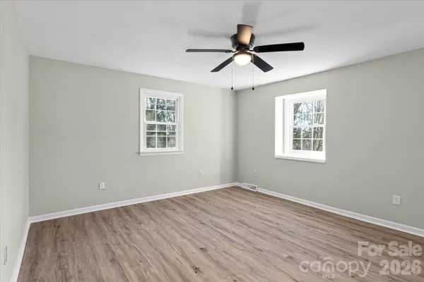 a view of a big room with wooden floor ceiling fan and windows