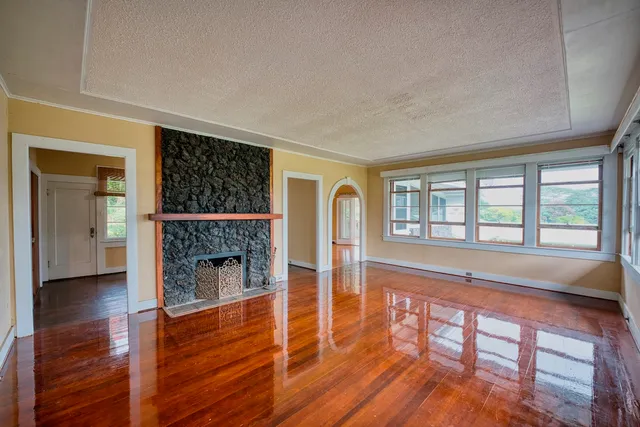 a view of empty room with wooden floor and fireplace