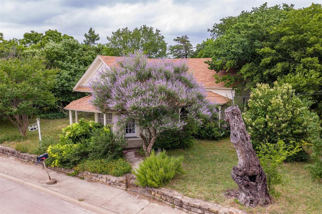 1007 West Belt Line Road Cedar Hill, TX 75104 - Photo 20 of 30 Charming residence featuring a welcoming front porch with white columns, a distinctive purple-blossomed tree, and an established lawn