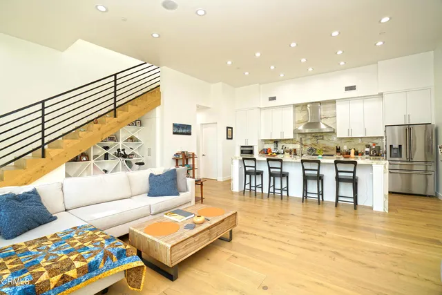 a living room with furniture and kitchen view with wooden floor
