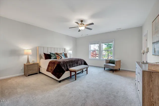 a spacious bedroom with a bed a dresser and next to a window
