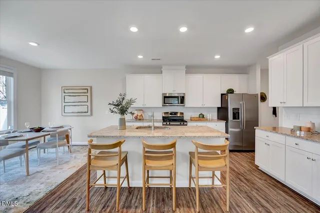 a kitchen with refrigerator a stove and chairs