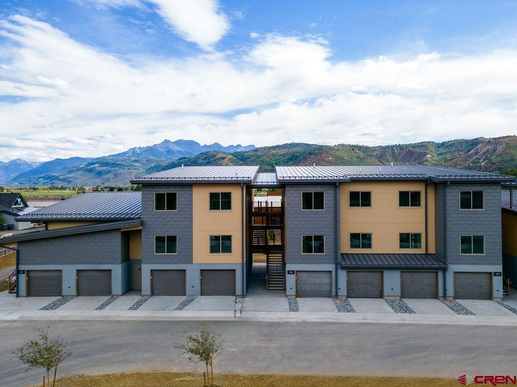 174 Alpine Lane, Unit 201 Ridgway, CO 81432 - Photo 2 of 27 a view of a white house with large windows and a small yard