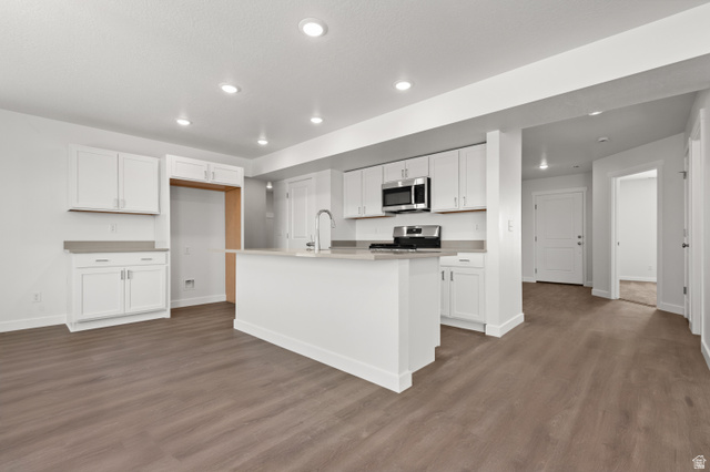 1554 Pheasant Road Eagle Mountain, UT 84005 - Photo 9 of 29 Kitchen featuring white cabinets, a center island with sink, dark wood finished floors, stainless steel appliances, and recessed lighting