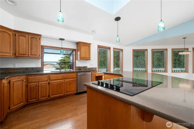a open kitchen with granite countertop a stove a sink a dining table and chairs with wooden floor