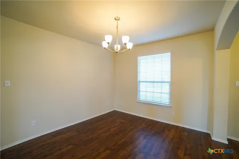 a view of a room with wooden floor chandelier and a window