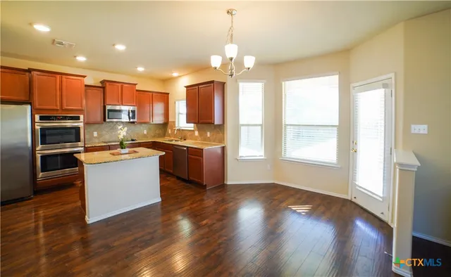 a kitchen with a refrigerator and a stove top oven