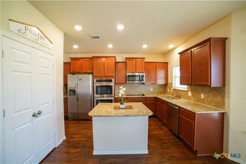 a kitchen with stainless steel appliances granite countertop a sink stove refrigerator and cabinets