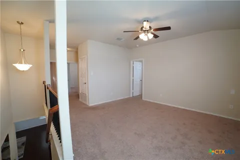 a view of an empty room with a ceiling fan and window