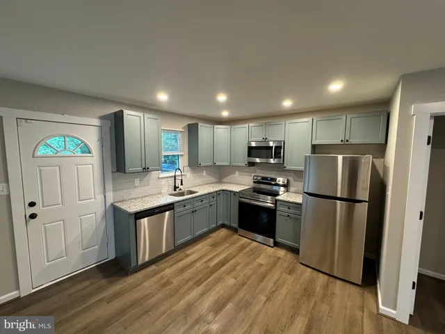 a kitchen with granite countertop stainless steel appliances a refrigerator a sink and a stove