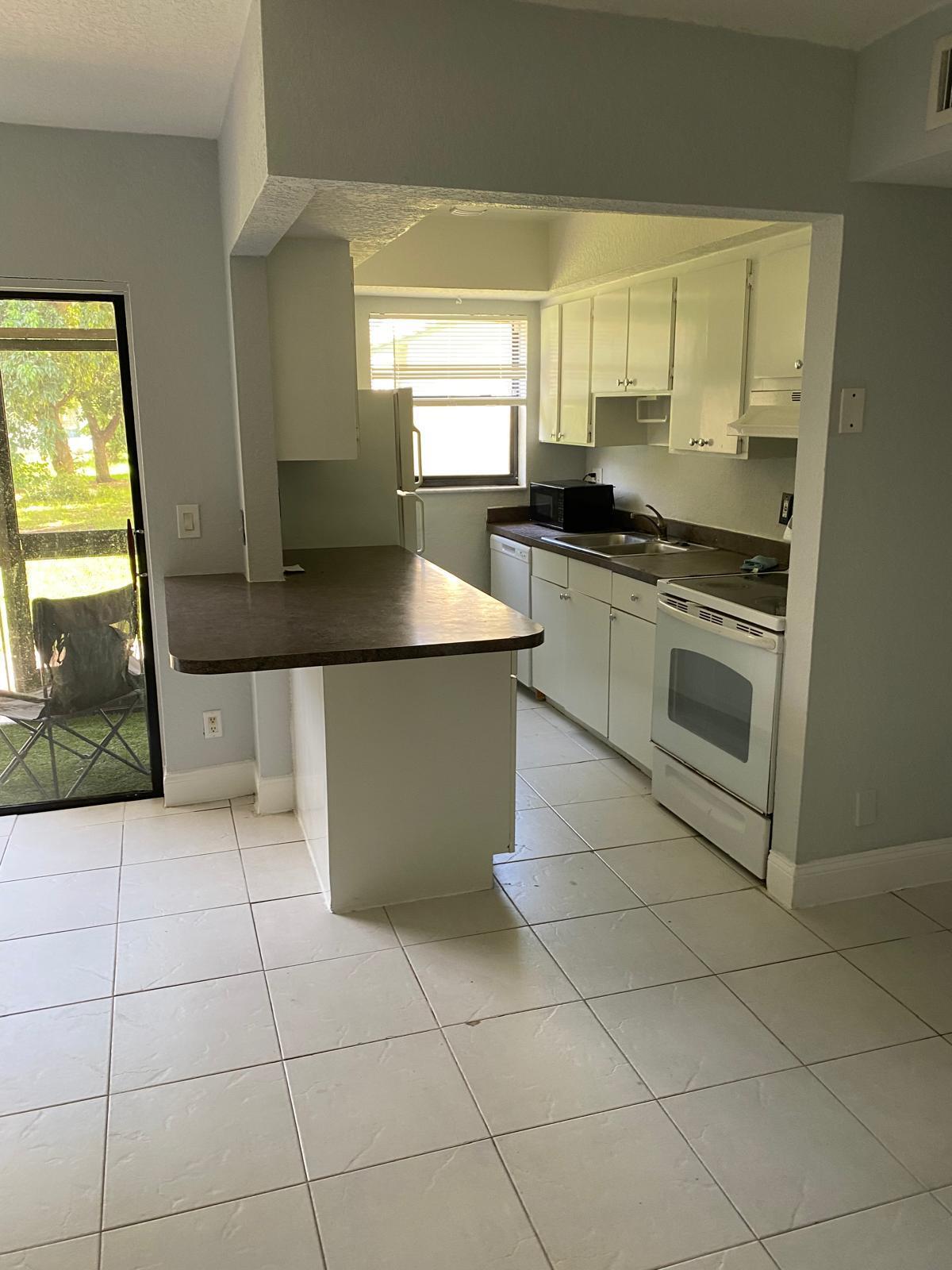 1195 Northwest 16th Avenue, Unit 10 Boca Raton, FL 33486 - Photo 3 of 13 a kitchen with a sink a counter top space cabinets and stainless steel appliances