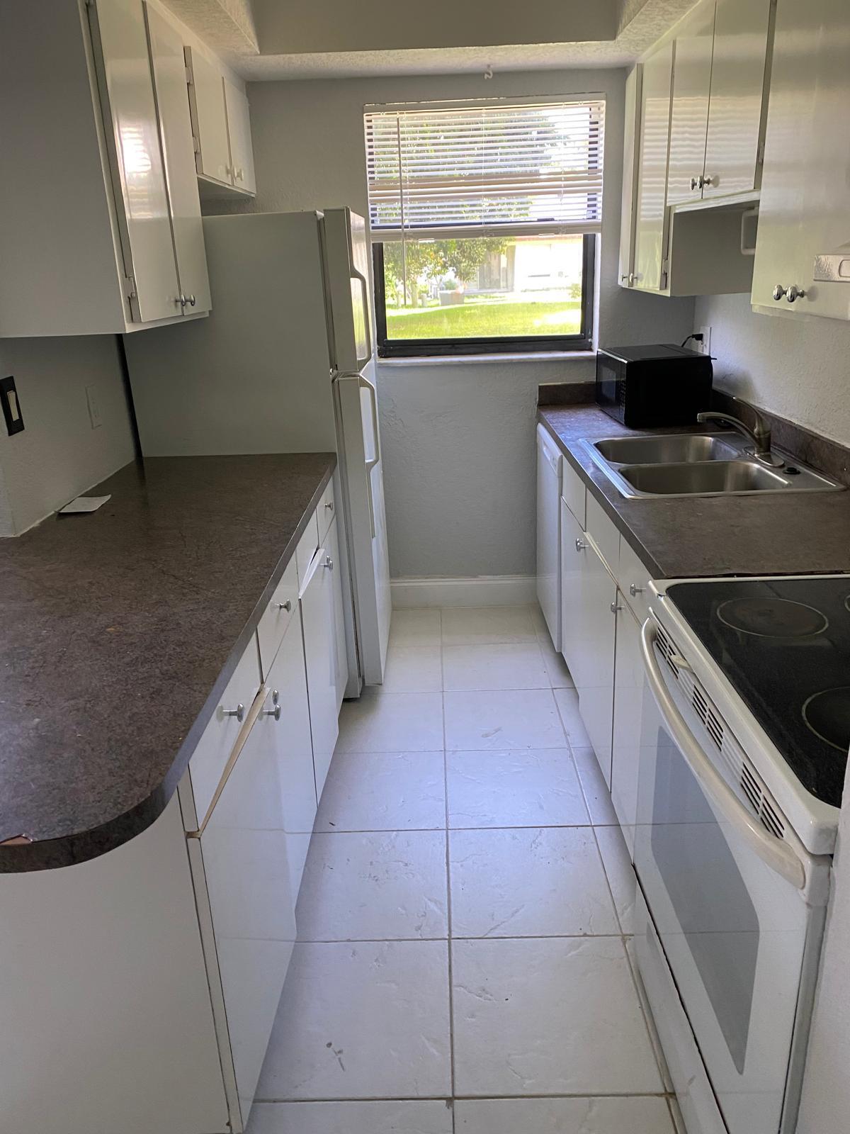 1195 Northwest 16th Avenue, Unit 10 Boca Raton, FL 33486 - Photo 7 of 13 a kitchen with stainless steel appliances granite countertop a sink a stove a washer and dryer